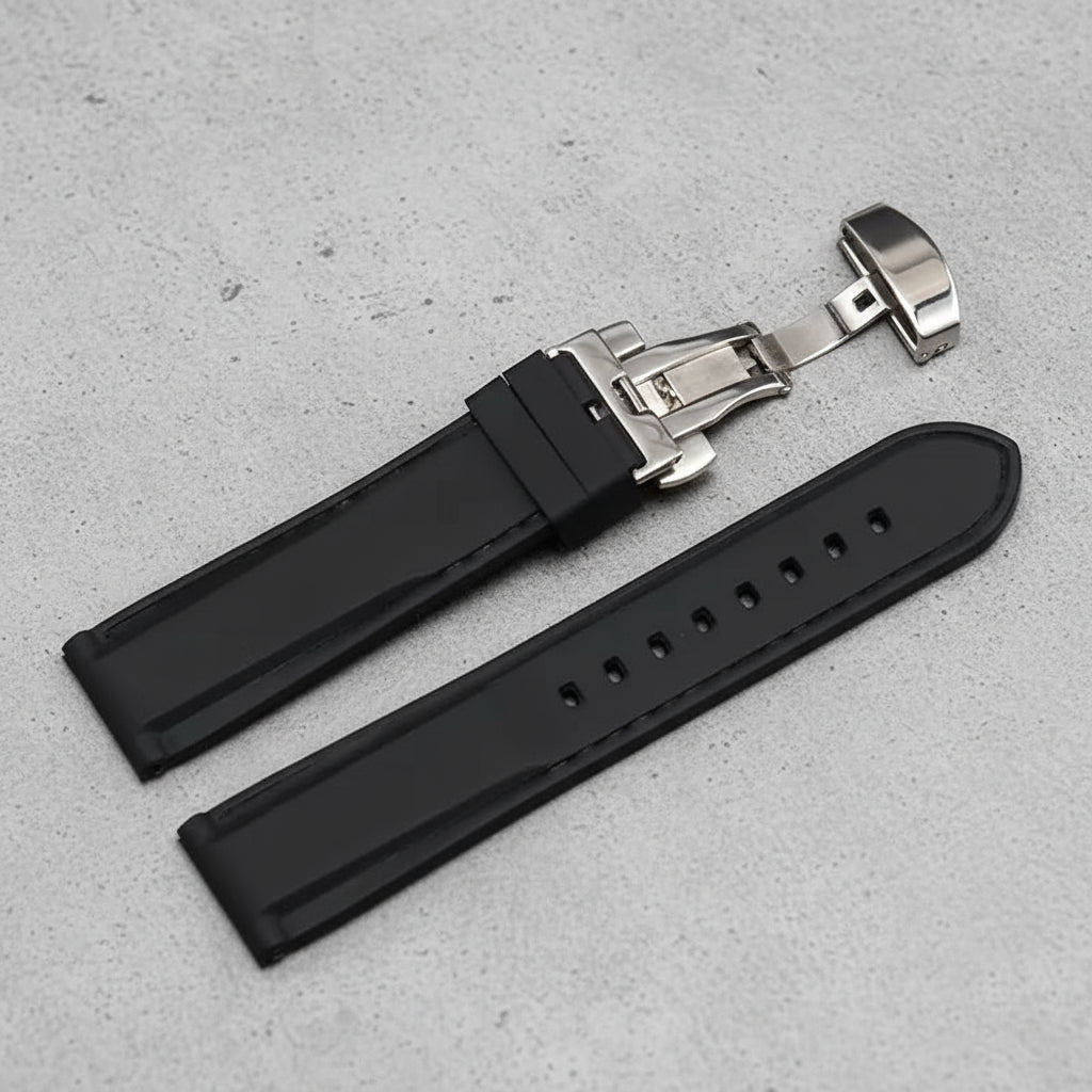 Black rubber watch strap with black stitching and a silver butterfly clasp