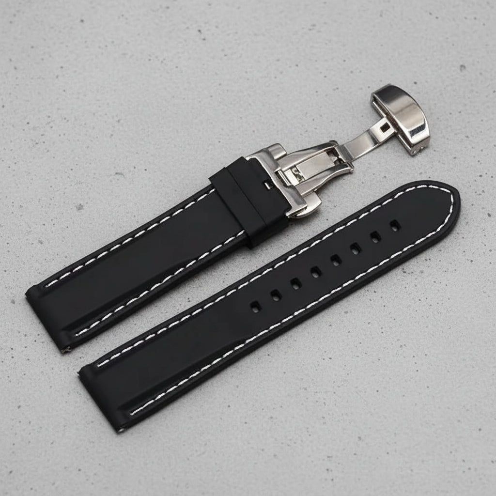 Black rubber watch strap with white stitching and a silver butterfly clasp
